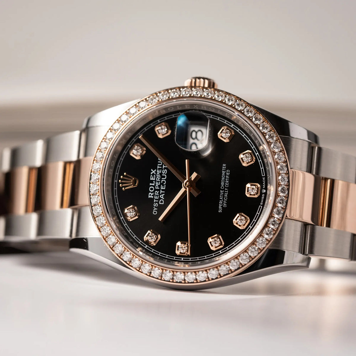 Detailaufnahme der seitlich auf dem Uhrengehäuse liegenden Rolex Datejust 36 126218RBR in Stahl-Roségold mit schwarzem Diamant-Zifferblatt und Diamant-Lünette im Factory-Besatz