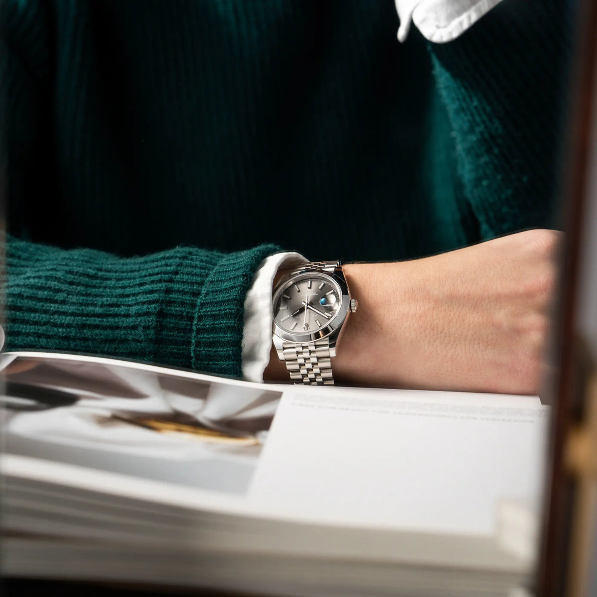 Mann in grünem Pullover trägt die Rolex Datejust 41 der Referenz 126300 mit grauem Zifferblatt und glatter Lünette am Jubilee-Stahl-Armband