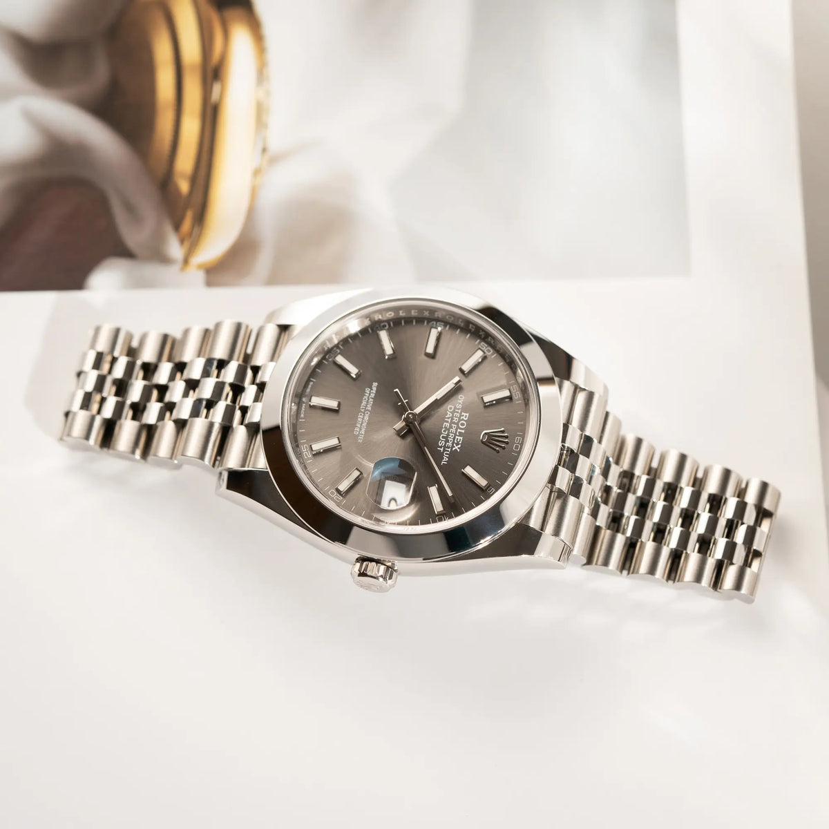 Produktfotografie der liegenden Rolex Datejust 41 der Referenz 126300 mit grauem Zifferblatt und glatter Lünette am Jubilee-Stahl-Armband