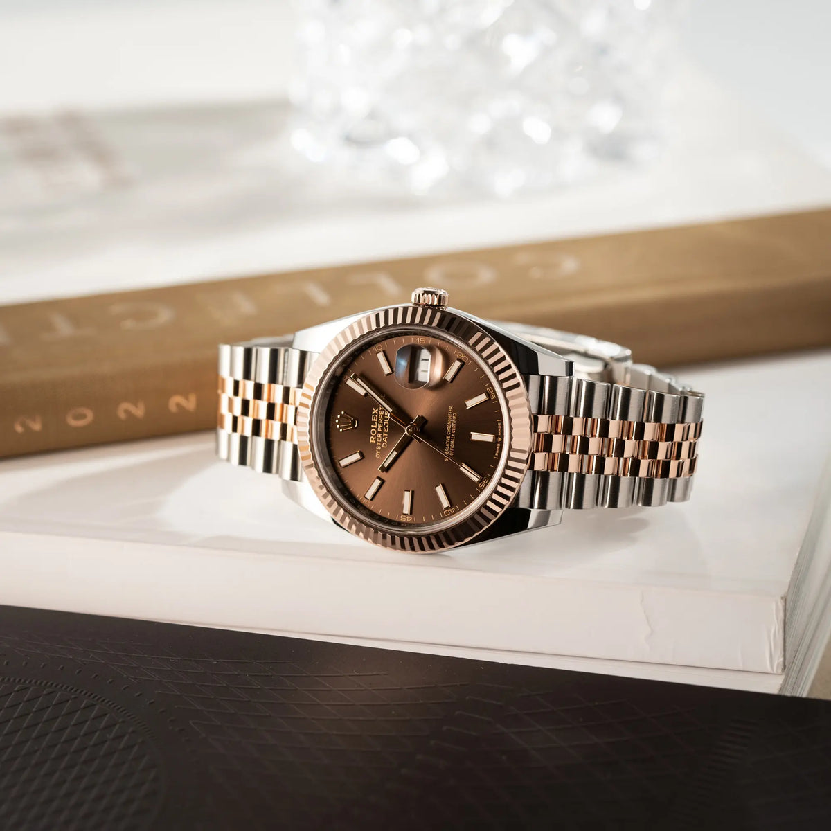 Produktfotografie der seitlich auf dem Uhrengehäuse liegenden bicolor Rolex Datejust 41 der Referenz 126331 Chocolate in Stahl-Roségold mit einem zum Roségold passenden braunen Zifferblatt am zugehörigen Jubilee-Armband