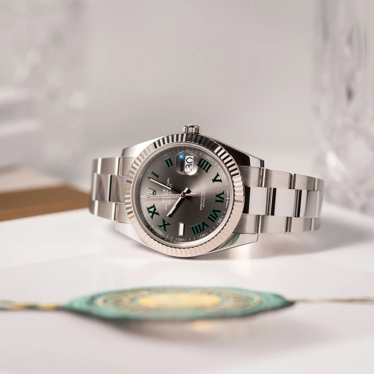 Produkfotografie der Rolex Datejust 41 der Referenz 126334 mit geriffelter Weißgold-Lünette und Oyster-Stahlband mit dem grauen Wimbledon-Zifferblatt mit schwarz-grünen Indizes