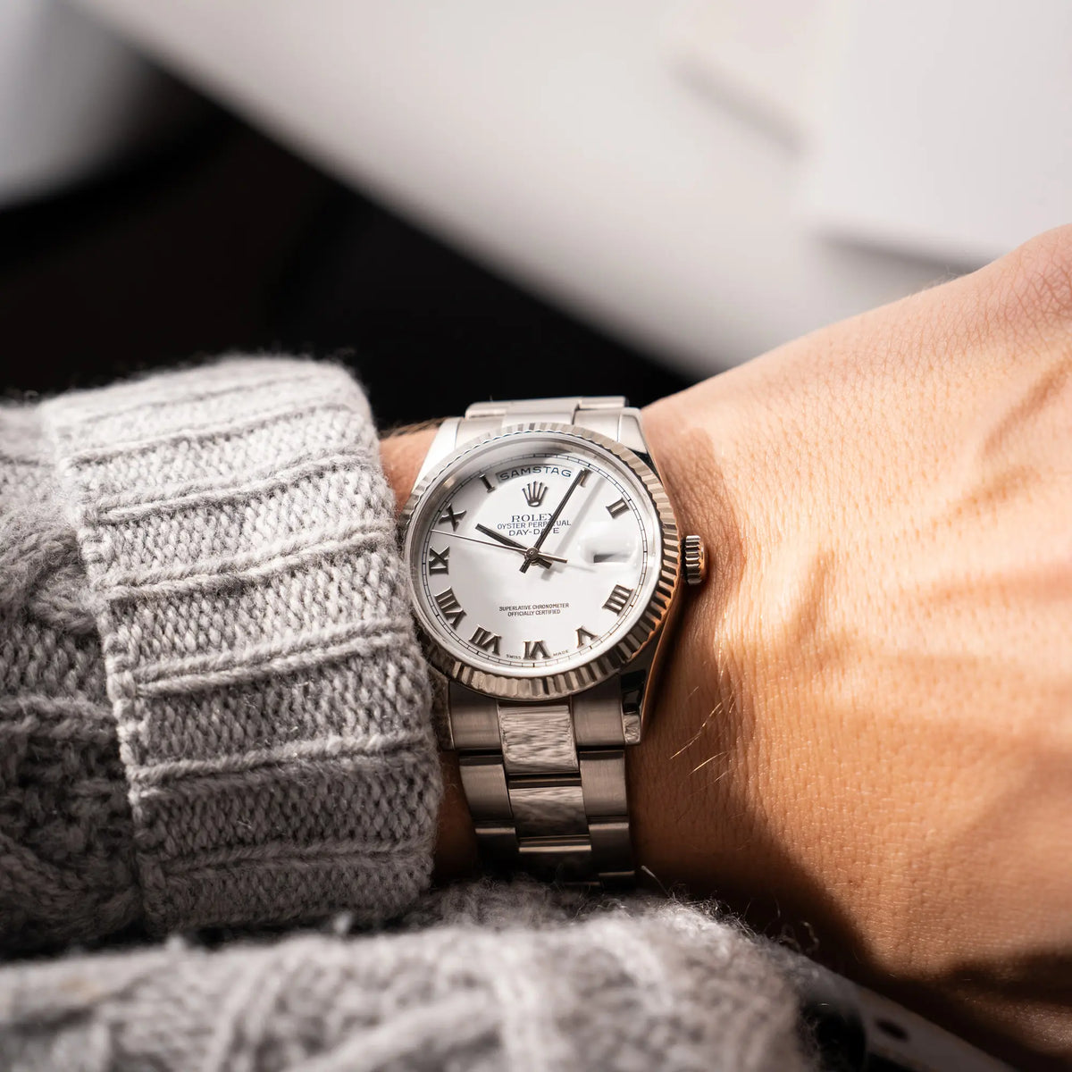 Mann trägt die Rolex Day-Date 36 Armbanduhr in Weißgold der Referenz 118239 mit weißem Zifferblatt mit römischen Indizes am Oyster-Weißgold-Armband für einen Wirstshot an seinem Handgelenk