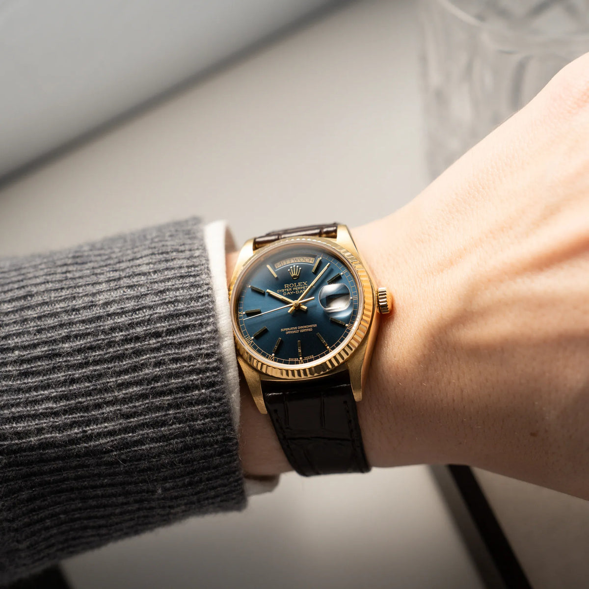 Wristshot mit der Rolex Day-Date 36 der Referenz 18038 in Gelbgold mit blauem Zifferblatt am braunen Lederband an einem Männerhandgelenk