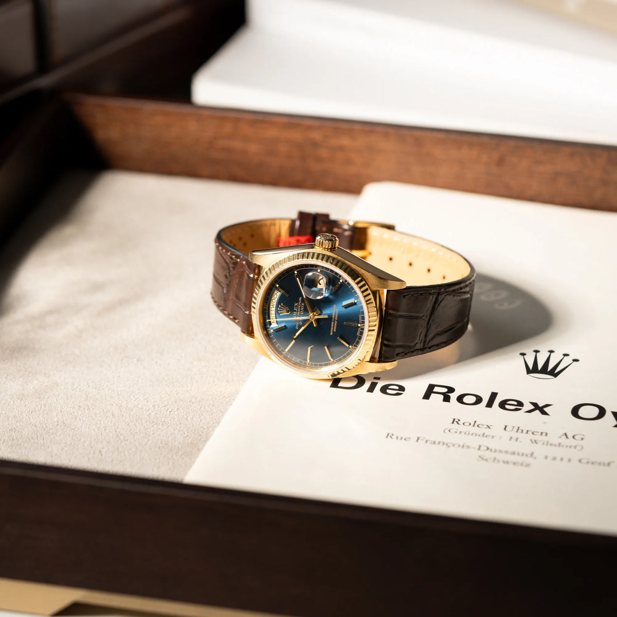 Produktfotografie der Rolex Day-Date 36 der Referenz 18038 in Gelbgold mit blauem Zifferblatt am braunen Lederband