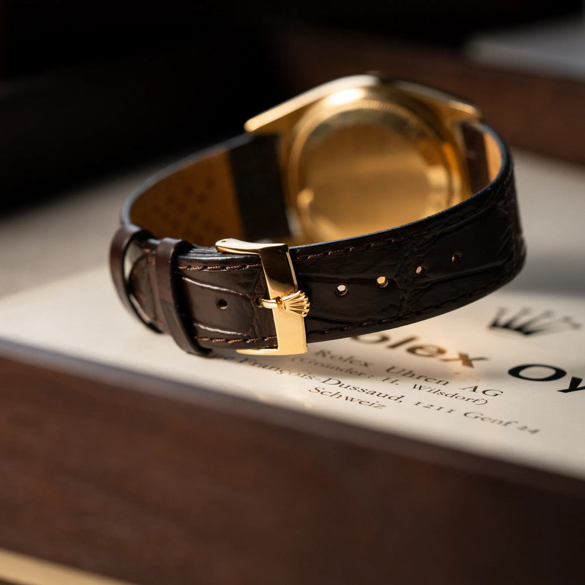 Produktfotografie der Rolex Day-Date 36 der Referenz 18038 in Gelbgold mit blauem Zifferblatt am braunen Lederband mit Fokus auf dem Lederband und der Dornschliesse mit Rolex-Krone
