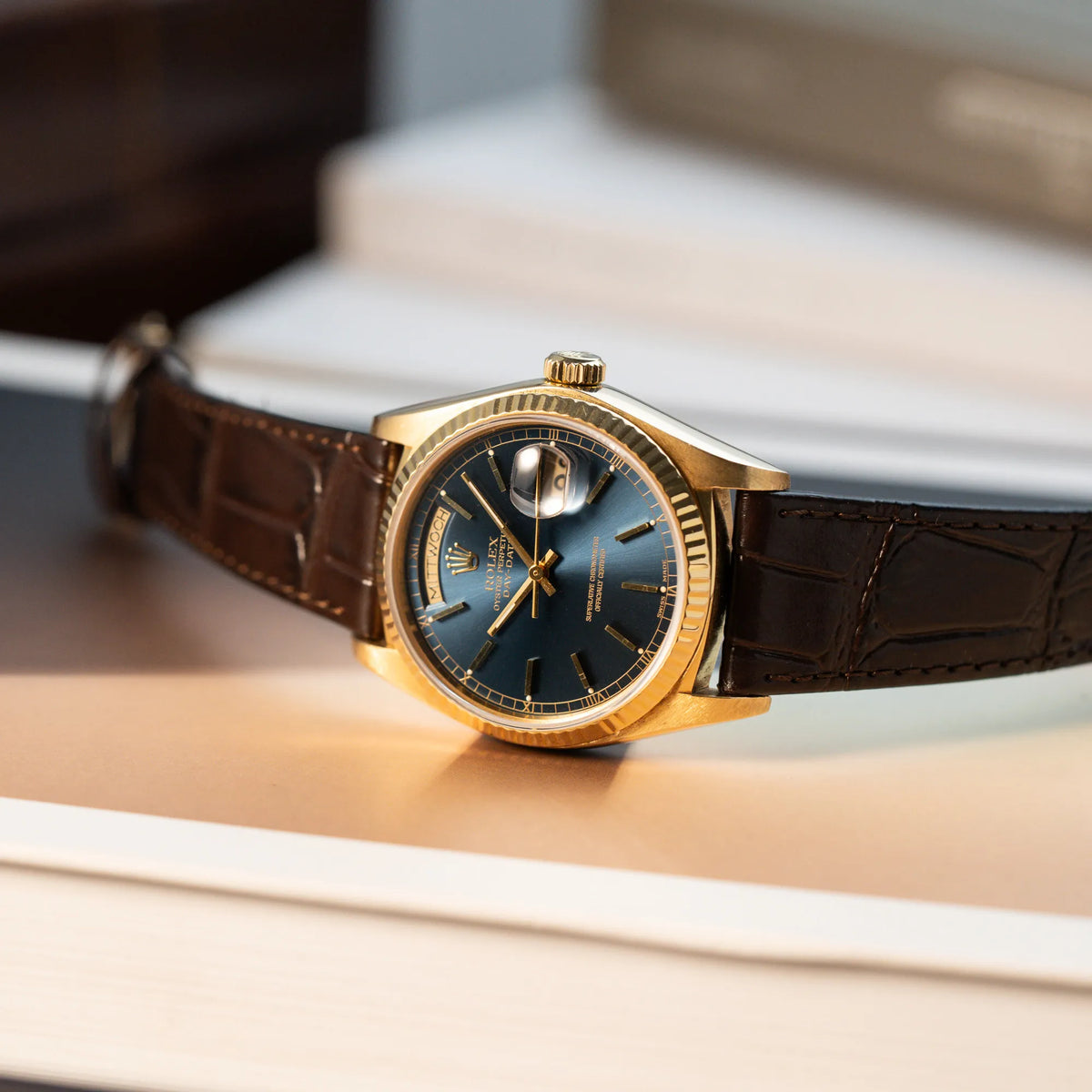 Produktfotografie der Rolex Day-Date 36 der Referenz 18038 in Gelbgold mit blauem Zifferblatt am braunen Lederband