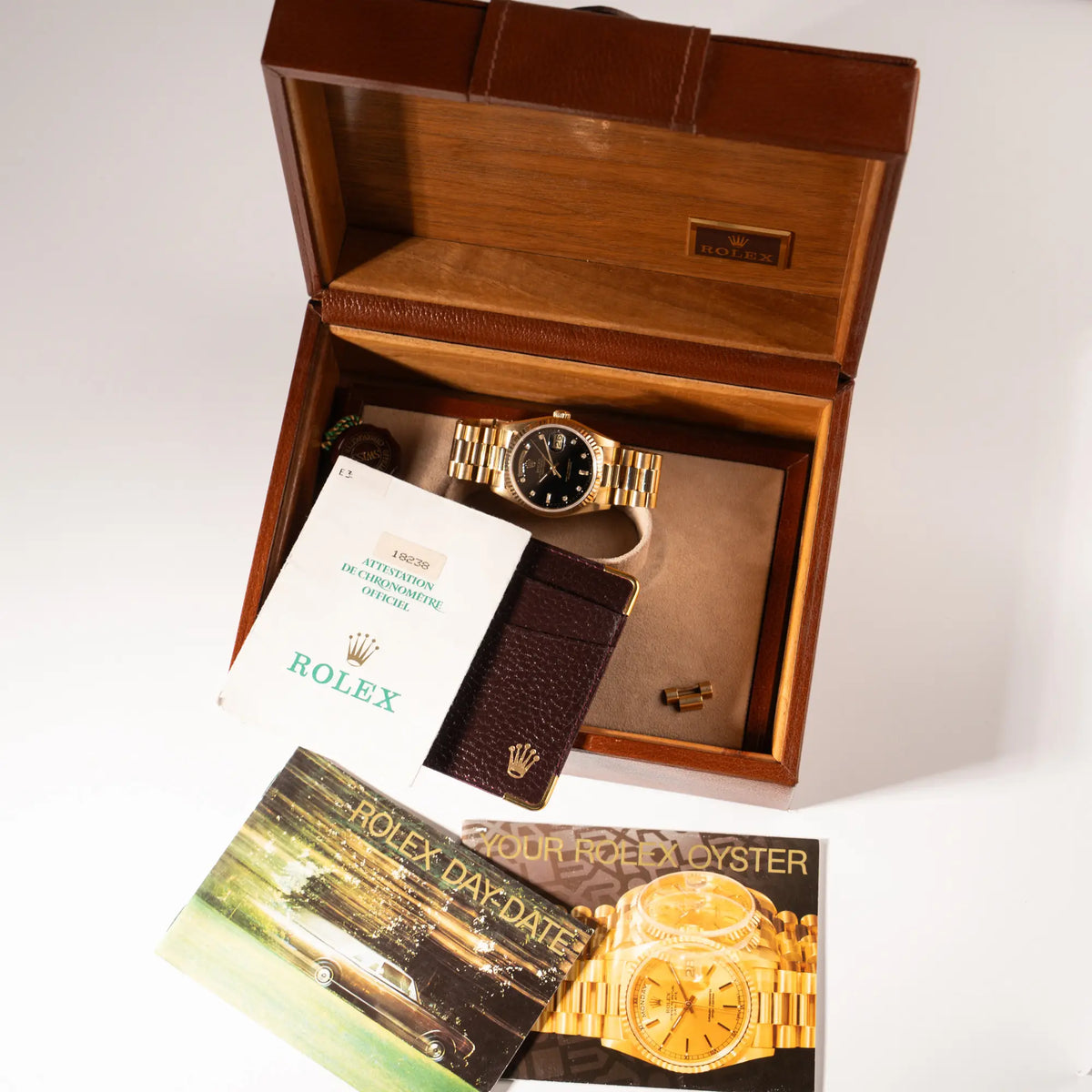 Lieferumfang zu der Rolex Day-Date 36 in Gelbgold mit der Referenznummer 18238 mit englisches Tagesanzeige, mit schwarzem Lack-Zifferblatt und Diamant-Indizes, betsehend aus Hangtag, Box, Papieren, Leder-Etui und Booklets