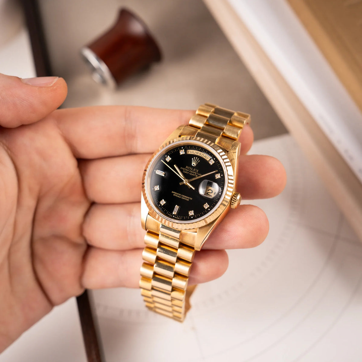 Mann hält die Rolex Day-Date 36 in Gelbgold mit der Referenznummer 18238 mit englischer Tagesanzeige, mit schwarzem Lack-Zifferblatt und Diamant-Indizes