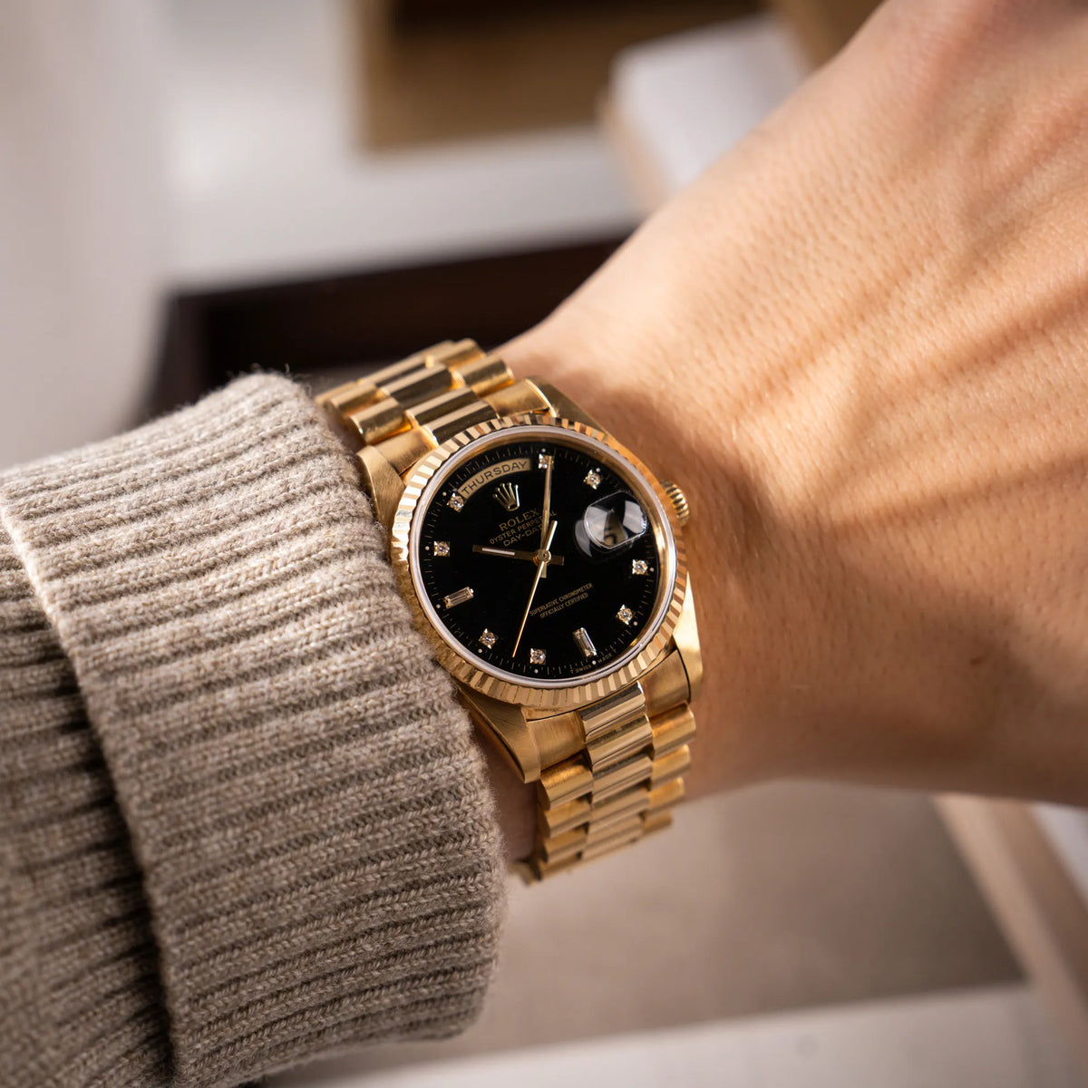 Mann trägt die Rolex Day-Date 36 in Gelbgold mit der Referenznummer 18238 mit englischer Tagesanzeige, mit schwarzem Lack-Zifferblatt und Diamant-Indizes an seinem Handgelenk