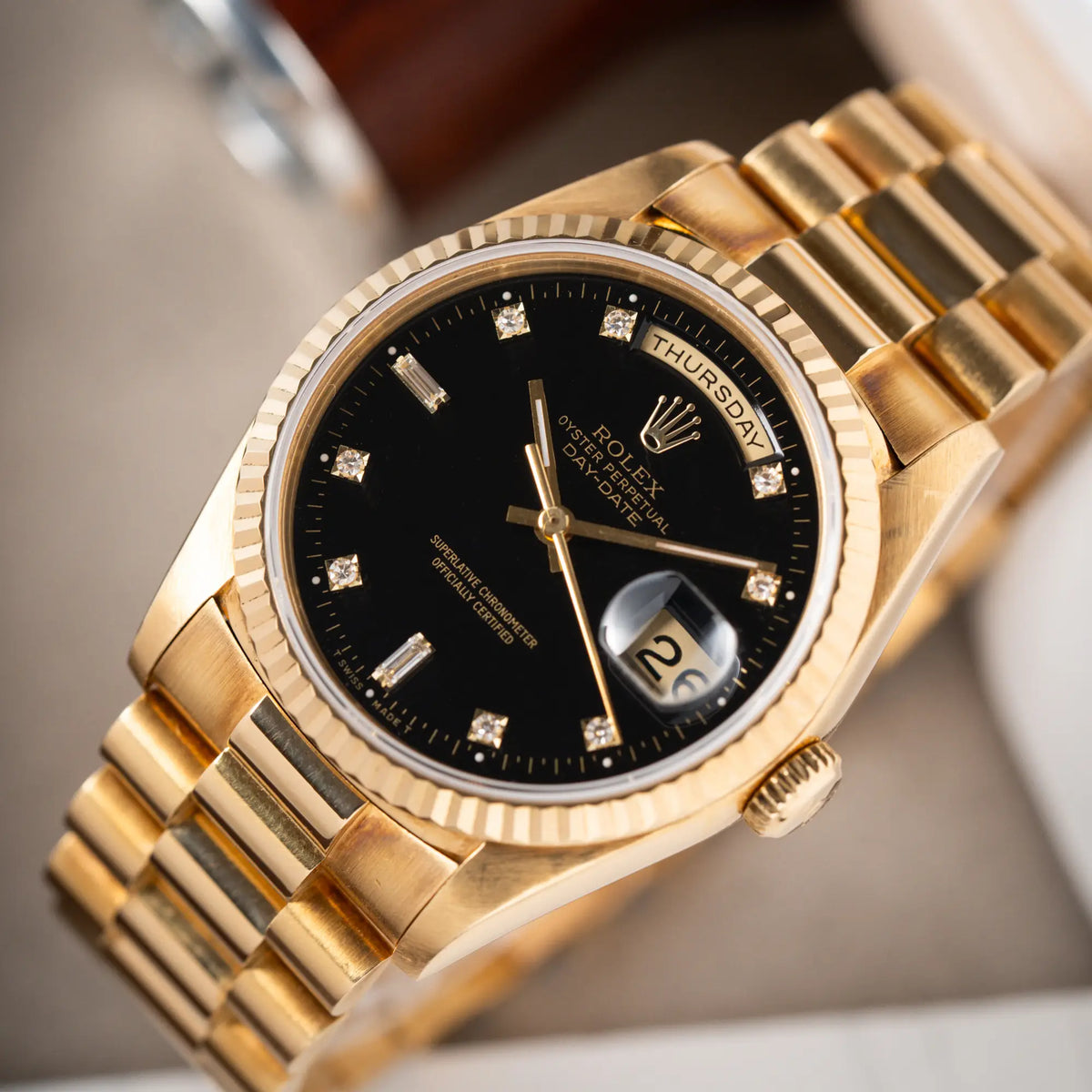 Produktfotografie Rolex Day-Date 36 in Gelbgold mit der Referenznummer 18238 mit englischer Tagesanzeige, mit schwarzem Lack-Zifferblatt und Diamant-Indizes mit Fokus auf dem Uhrenkopf