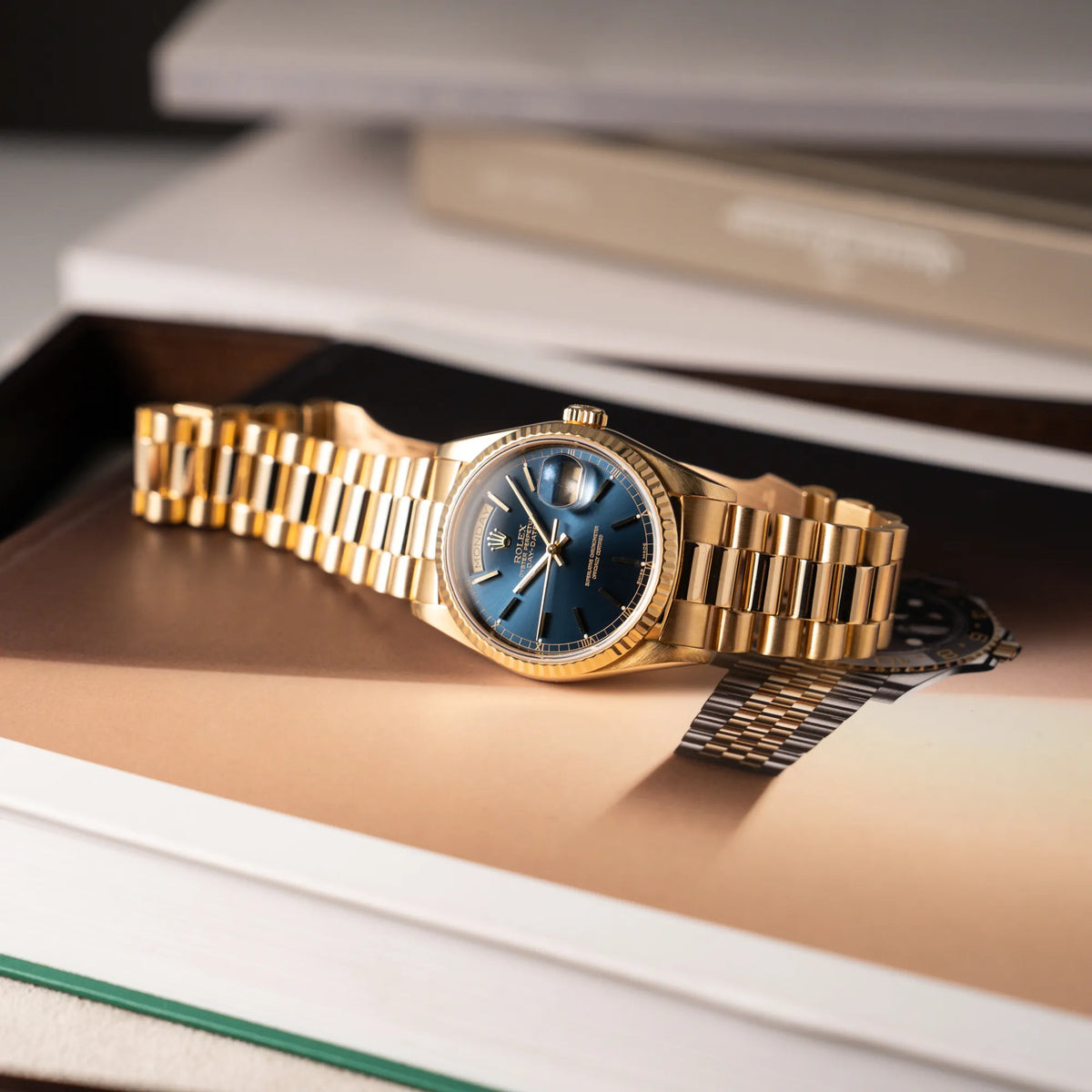 Produktfotografie der gelbgoldenen Rolex Day-Date 36 der Referenz 18238 mit blauem Zifferblatt und englisch-sprachiger Tagesanzeige