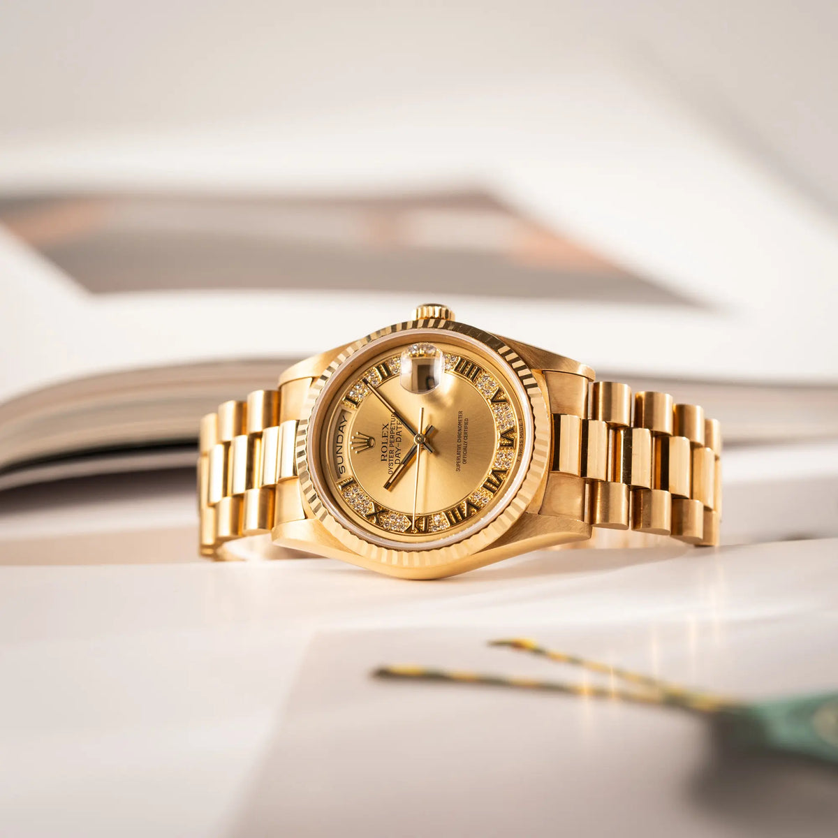 Gelbgoldene Rolex Day-Date 36 der Referenz 18238 mit einem seltenen Myriad-Dial mit Diamant-Kranz und römischen Indizes liegt seitlich auf der Gehäuseflanke