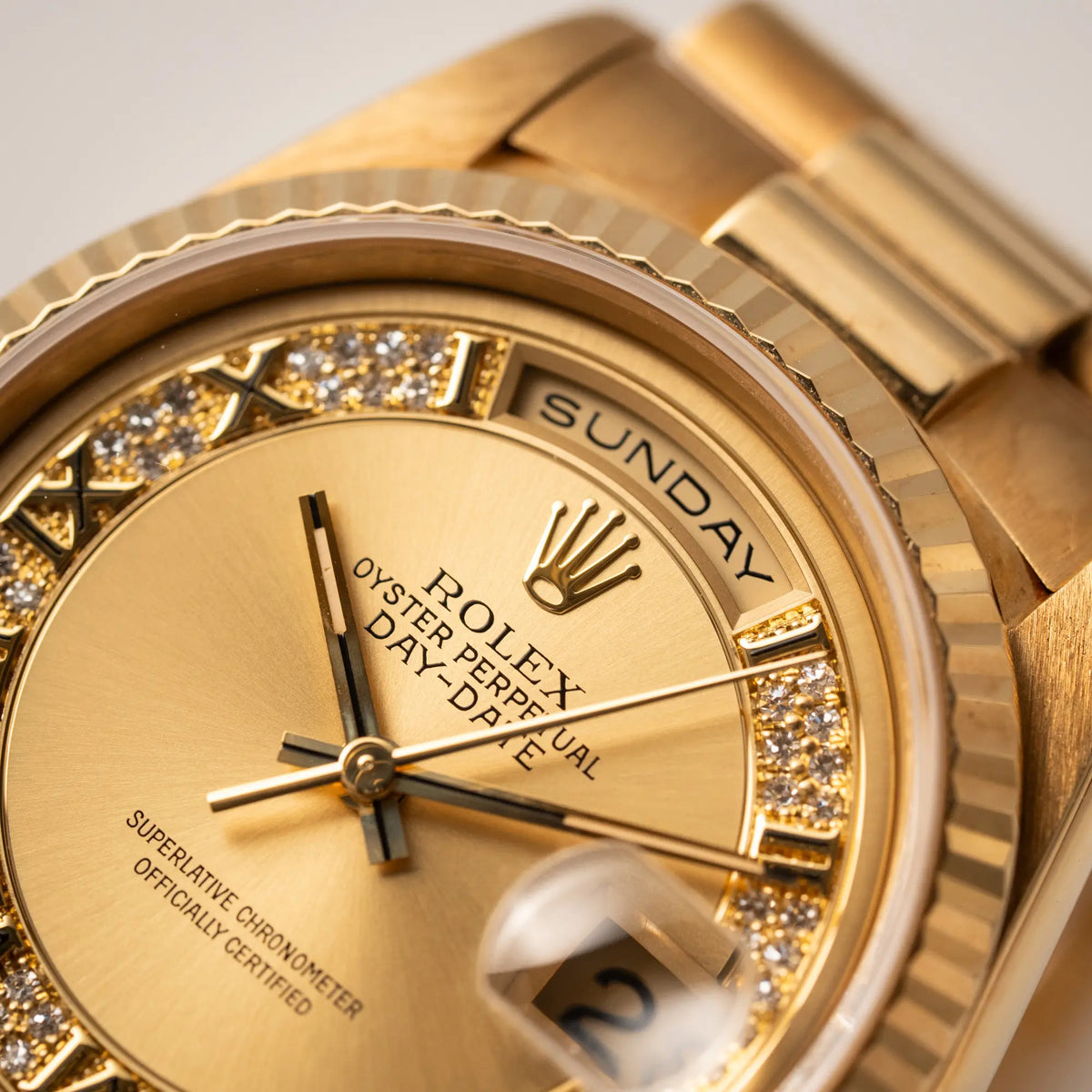 Detailaufnahme mit Fokus auf der englisch-sprachigen Wochentaganzeige der der gelbgoldenen Rolex Day-Date 36 der Referenz 18238 mit einem seltenen Myriad-Dial mit Diamant-Kranz und römischen Indizes