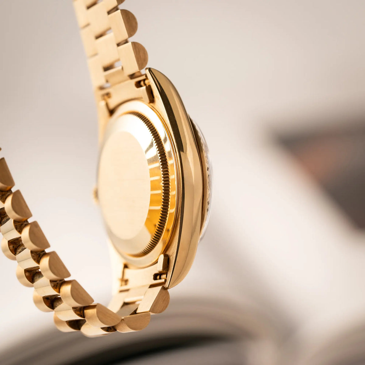 Produktfotografie der gelbgoldenen Rolex Day-Date 36 der Referenz 18238 mit einem seltenen Myriad-Dial mit Diamant-Kranz und römischen Indizes zeigt den Gehäuseboden und die seitliche Gehäuseflanke