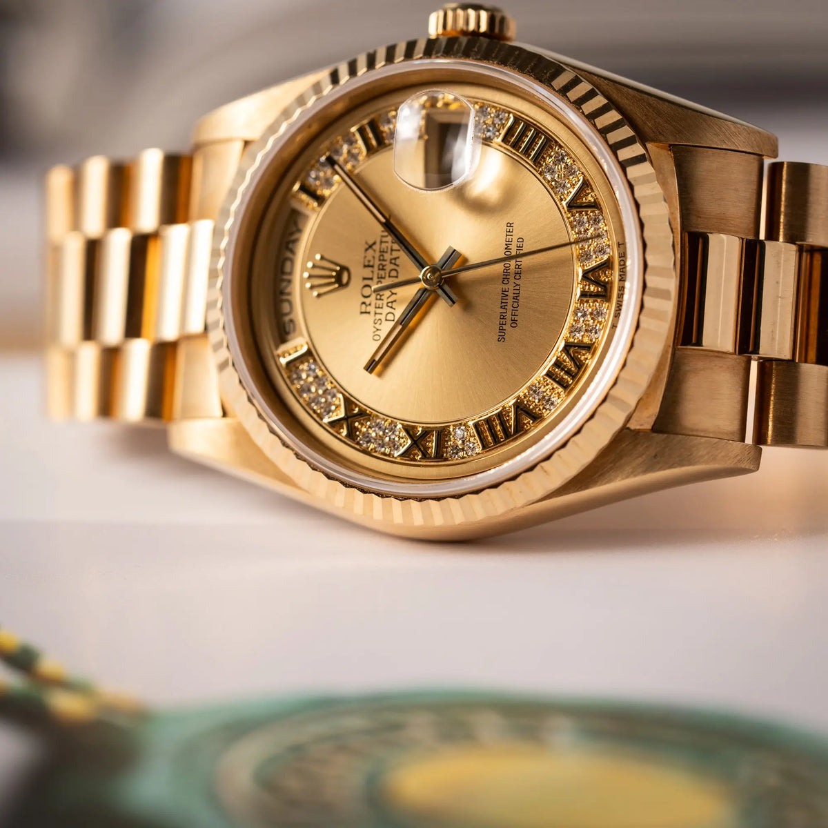 Detailaufnahme der seitlich auf dem Gehäuse liegenden gelbgoldenen Rolex Day-Date 36 der Referenz 18238 mit einem seltenen Myriad-Dial mit Diamant-Kranz und römischen Indizes
