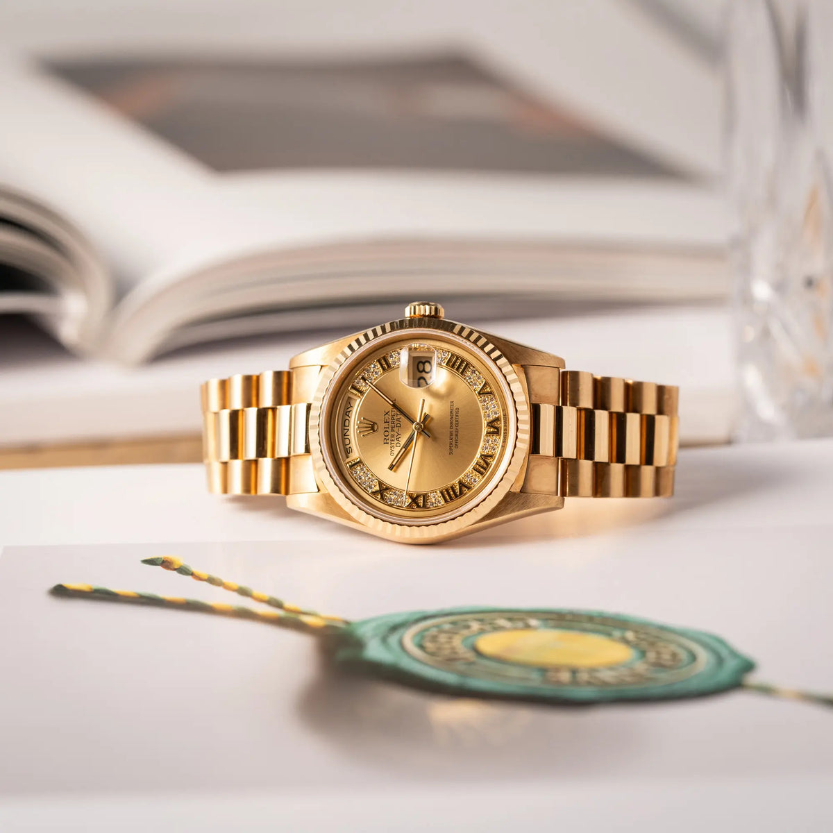 Gelbgoldene Rolex Day-Date 36 der Referenz 18238 mit einem seltenen Myriad-Dial mit Diamant-Kranz und römischen Indizes liegt auf einem Uhrenbuch