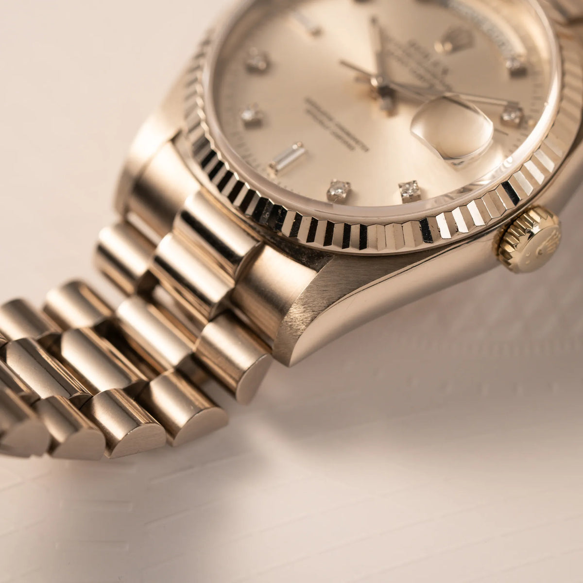 Produktfotografie der Rolex Day-Date der Referenz 18239 in 36 mm aus 18 karätigem Weißgold mit silbernem Diamant-Zifferblatt zeigt den unteren rechten Bandanstoß und eine Teil der geriffelten Lünette im Detail