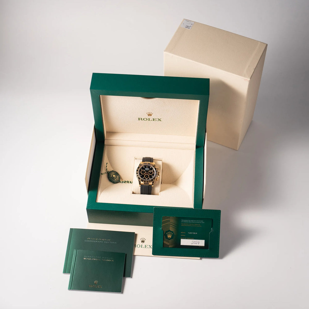 Lieferumfang zu der Rolex Daytona 126518LN mit Gelbgold-Gehäuse und schwarzem Zifferblatt am schwarzen Oysterflex-Armband aus Kautschuk, bestehend aus Box mit Umkarton, Hangtag, allen Booklets und originaler Rolex-Garantiekarte aus 2024