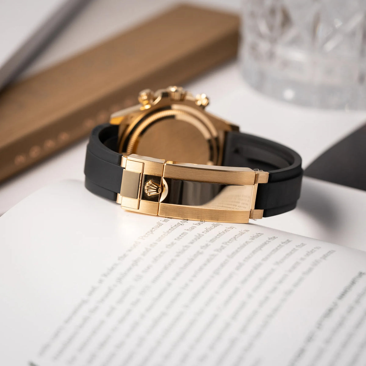 Produktfotografie der Rolex Daytona 126518LN mit Gelbgold-Gehäuse und schwarzem Zifferblatt am schwarzen Oysterflex-Armband aus Kautschuk zeigt die gelbgoldene Schliesse