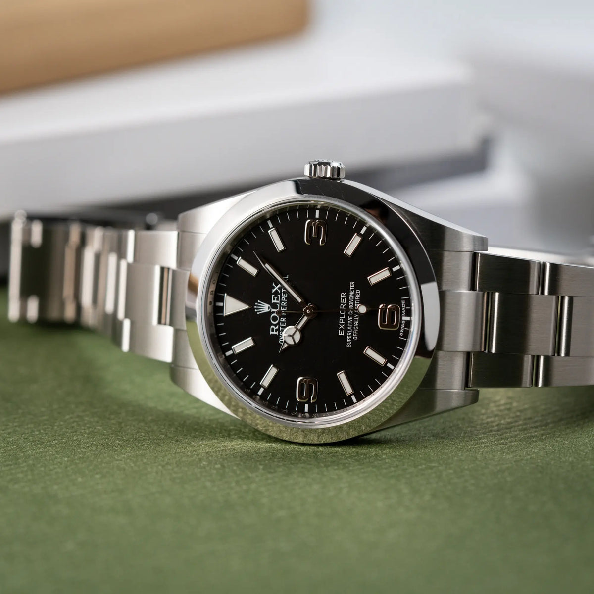 Detailaufnahme der seitlich auf der Gehäuseflanke liegenden Rolex Explorer der Referenz 214270 mit 39mm Oyster-Gehäuse und dem klassischen 2-6-9-Zifferblatt in schwarz