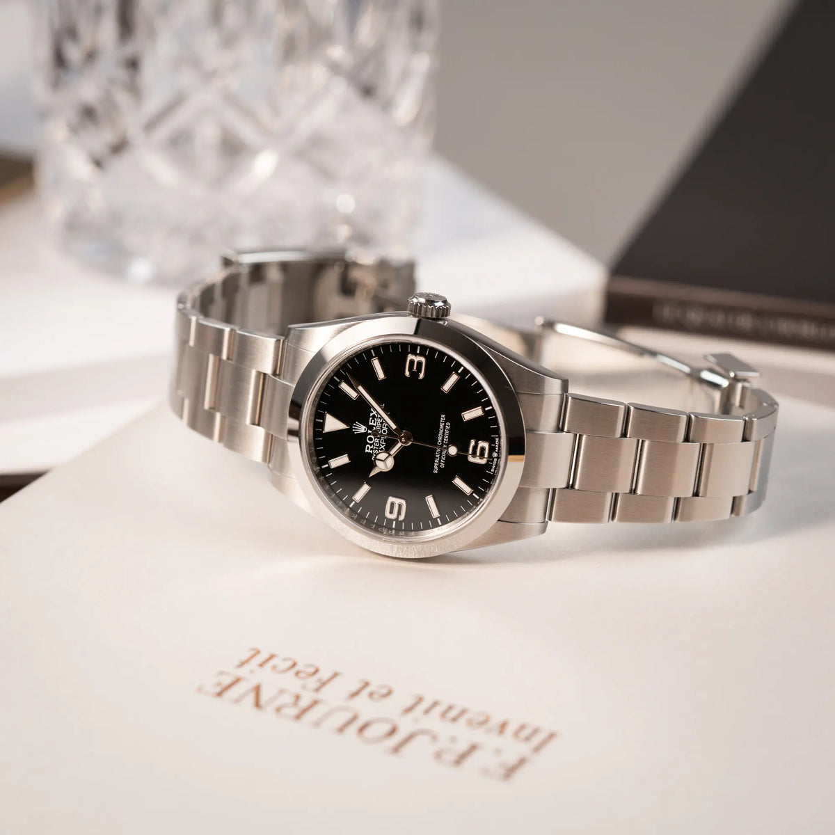 Produktfotografie der seitlich auf dem Gehäuse liegenden Rolex Explorer 40 Armbanduhr der Referenz 224270 mit dem klassischen 3-6-9-Explorer-Zifferblatt