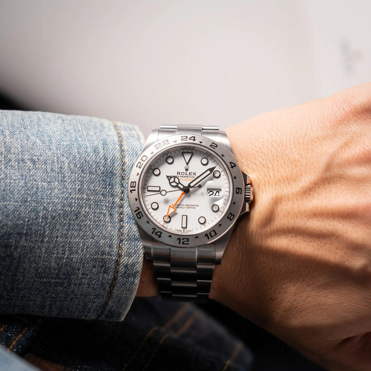 Mann trägt die Rolex Explorer II der Referenz 226570 am Oyster-Stahlband mit dem weißen Polar-Zifferblatt und dem typischen orangen 24-Stunden-Zeiger an seinem Handgelenk