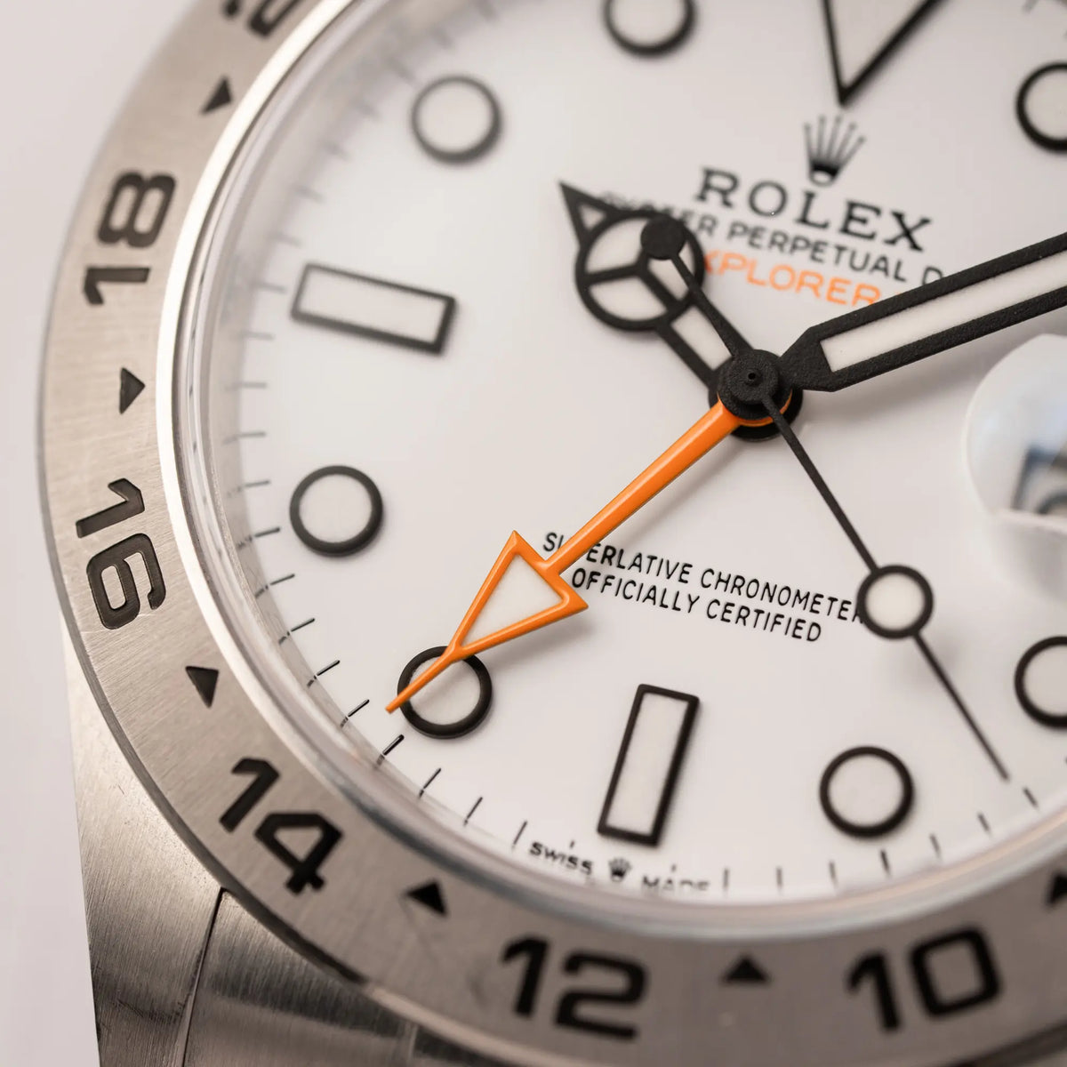 Detailaufnahme des orangen 24-Stunden-Zeigers von der Rolex Explorer II der Referenz 226570 am Oyster-Stahlband mit dem weißen Polar-Zifferblatt