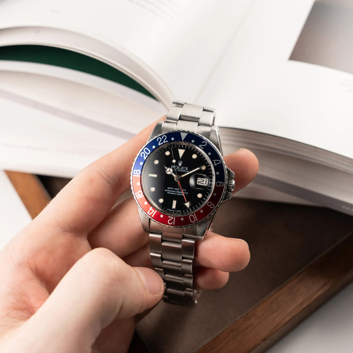 Mann hält die Rolex GMT Master 1675 mit dem Nickname Pepsi mit blau-roter Lynette in seiner Hand