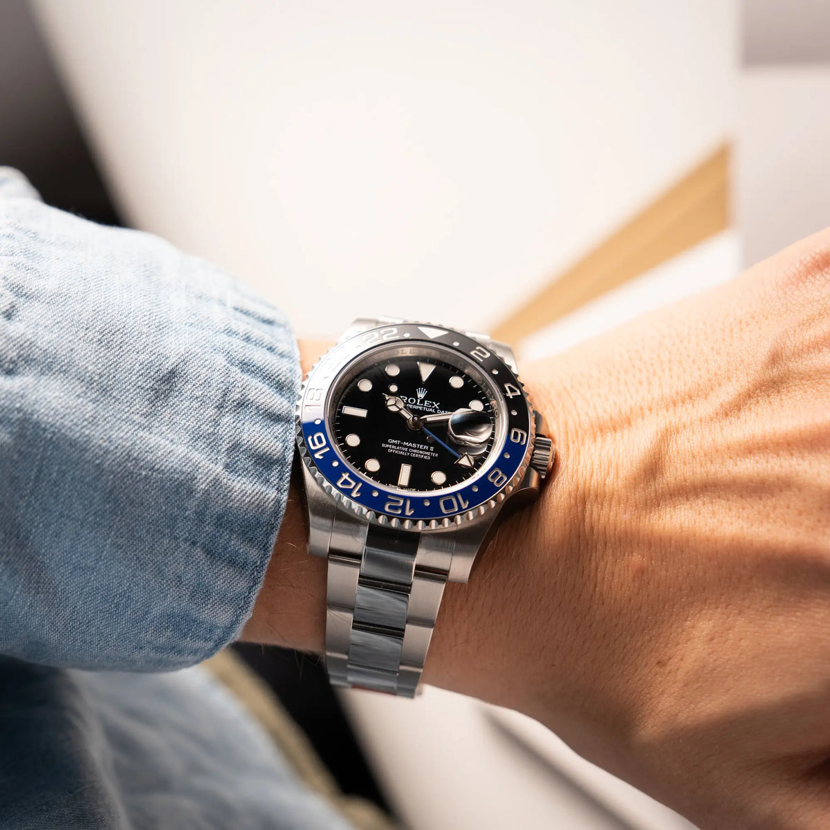 Mann präsentiert die Rolex GMT-Master II der Referenz 116710BLNR mit dem Nickname "Batman" mit der schwarz blauen Keramik-Lünette am Oyster-Stahlband im verklebten Neuzustand an seinem Handgelenk