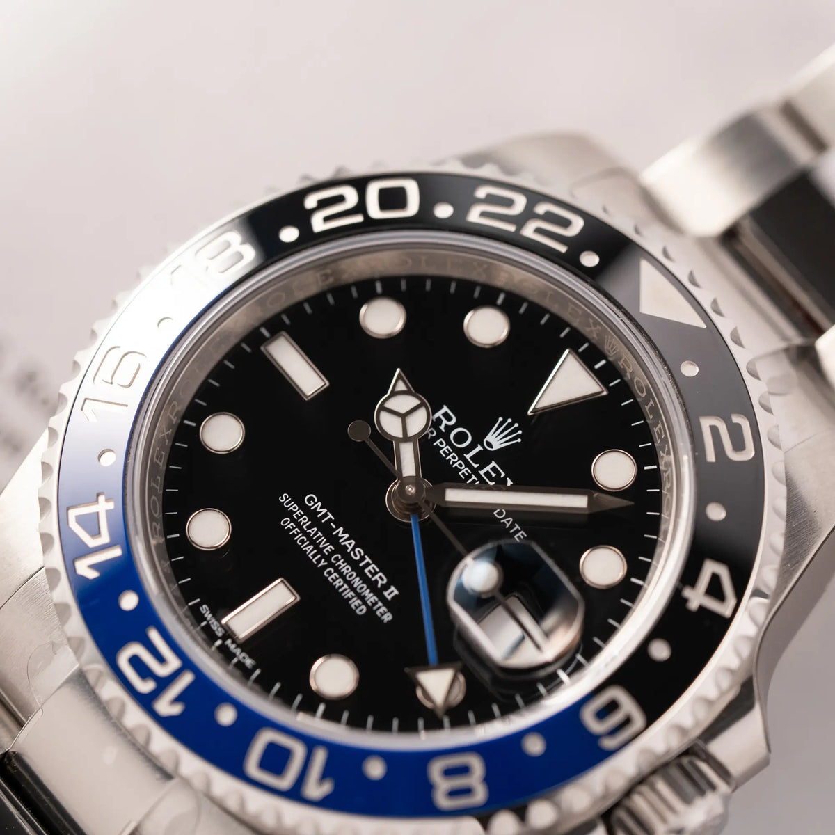 Detailaufnahme des Uhrenkopfes von der Rolex GMT-Master II der Referenz 116710BLNR mit dem Nickname "Batman" mit der schwarz blauen Keramik-Lünette am Oyster-Stahlband im verklebten Neuzustand