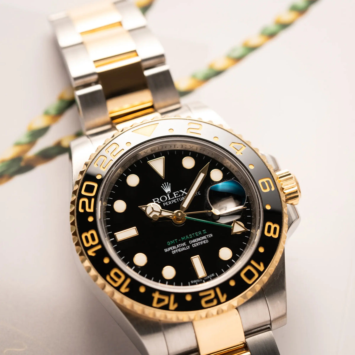 Detailaufnahme des Uhrenkopfes von der Rolex GMT-Master II der Referenz 116713LN in Stahl-Gold mit schwarzem Zifferblatt und dem grünen GMT-Zeiger