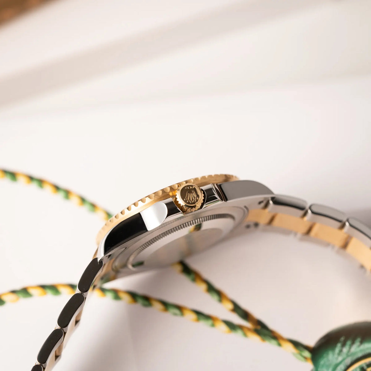 Produktfotografie der Rolex GMT-Master II der Referenz 116713LN in Stahl-Gold mit schwarzem Zifferblatt und dem grünen GMT-Zeiger zeigt die seitliche Gehäuseflanke mit goldener Aufzugskrone