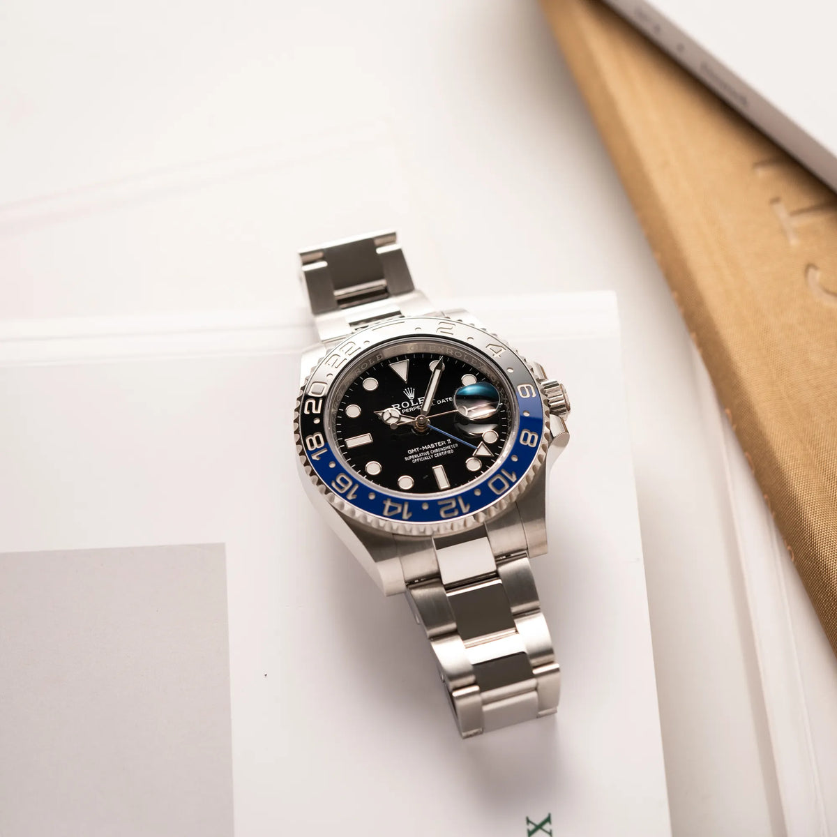 Produktfotografie zeigt die flach auf dem Uhrenband liegende Rolex GMT-Master II 126710BLNR mit dem Nickname Batman und der typischen Kombination aus blau-schwarzer Keramik-Lünette und schwarzem Zifferblatt