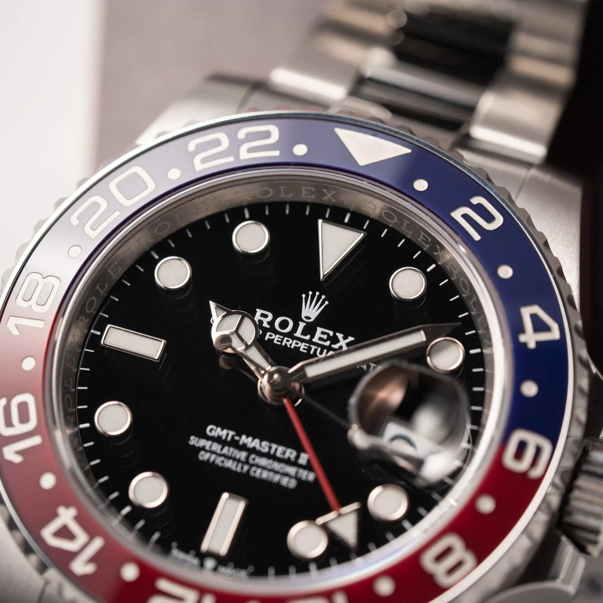 Detailaufnahme der Rolex GMT-Master II der Referenz 126710BLRO mit der blau-roten Pepsi-Lünette in Keramik am Oyster-Stahl-Armband im ungetragenen Zustand mit Fokus auf dem Rolex Oyster Perpetual Schriftzug bei 12 Uhr