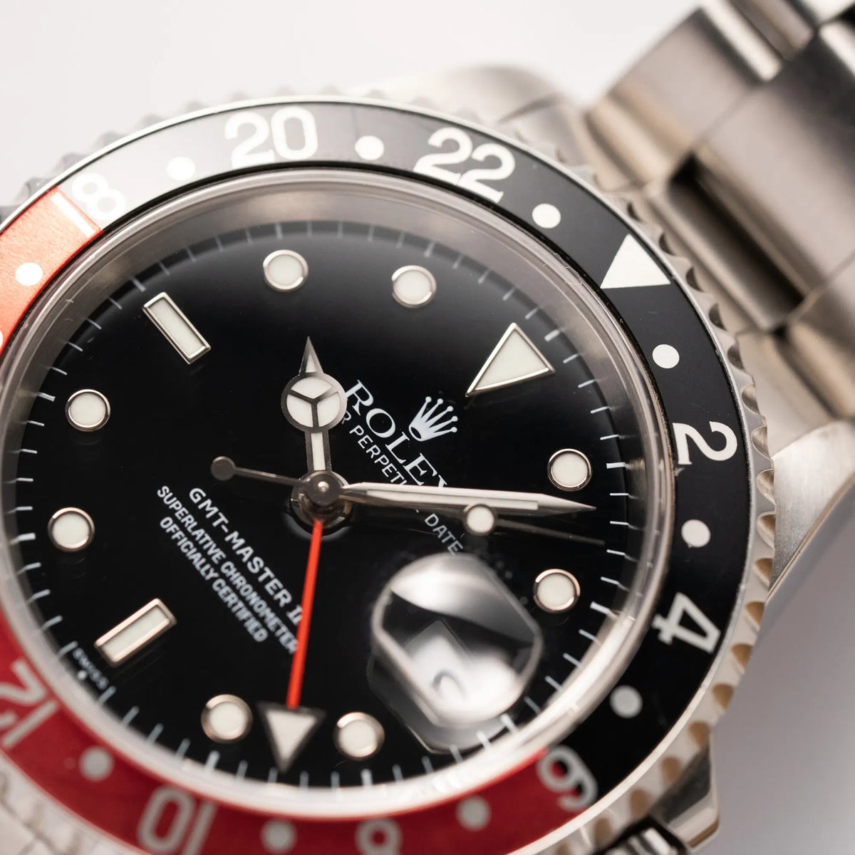 Makroaufnahme derRolex GMT-Master II der Referenz 16710 2000 mit schwarz-roter Coke-Lünette und dem für das Jahr 2000 typische "Swiss Only" - Zifferblatt mit Fokus auf dem Zeigersatz