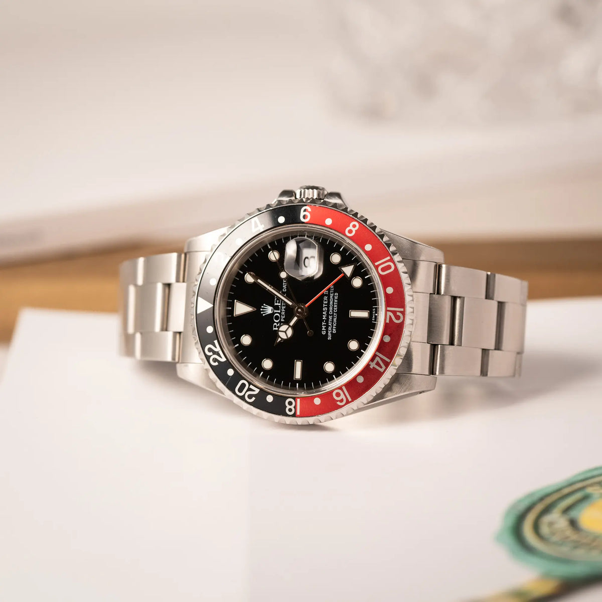Seitliche Gehäuseflanke der Rolex GMT-Master II der Referenz 16710 2000 mit schwarz-roter Coke-Lünette und dem für das Jahr 2000 typische "Swiss Only" - Zifferblatt liegt auf einem Uhrenbuch