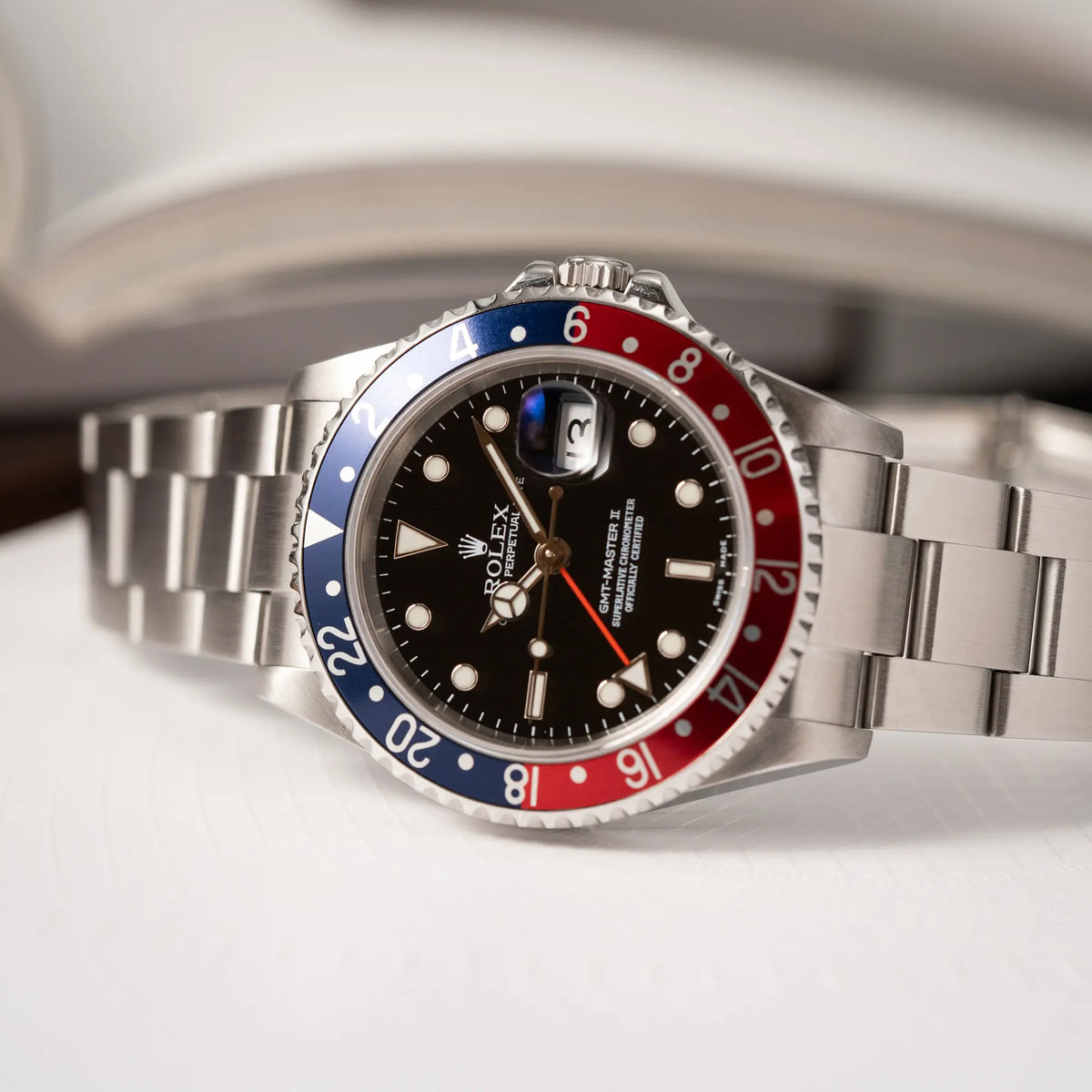 Produktfotografie der Rolex GMT-Master II Pepsi der Referenz 16710 mit der blau-roten Aluminium-Lünette während die Uhr auf der seitlichen Gehäuseflanke