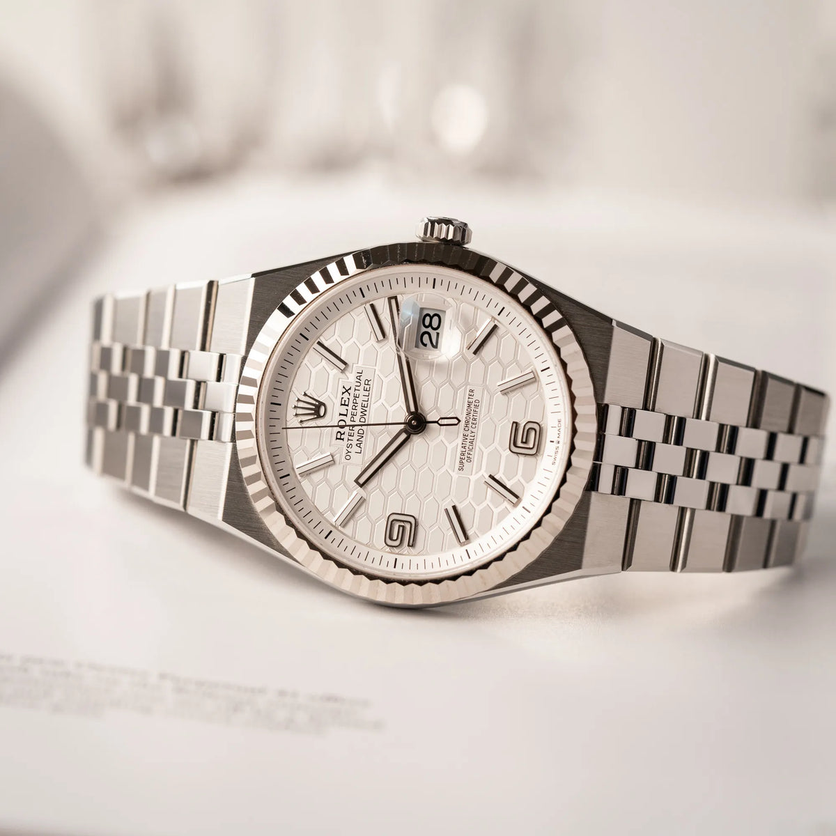Produktfotografie als Titelbild für die Rolex Land-Dweller 40 der Referenz 127334 im neuwertigen Zustand mit dem weißen Zifferblatt in Waben-Struktur am neuen Flat-Jubilee-Armband