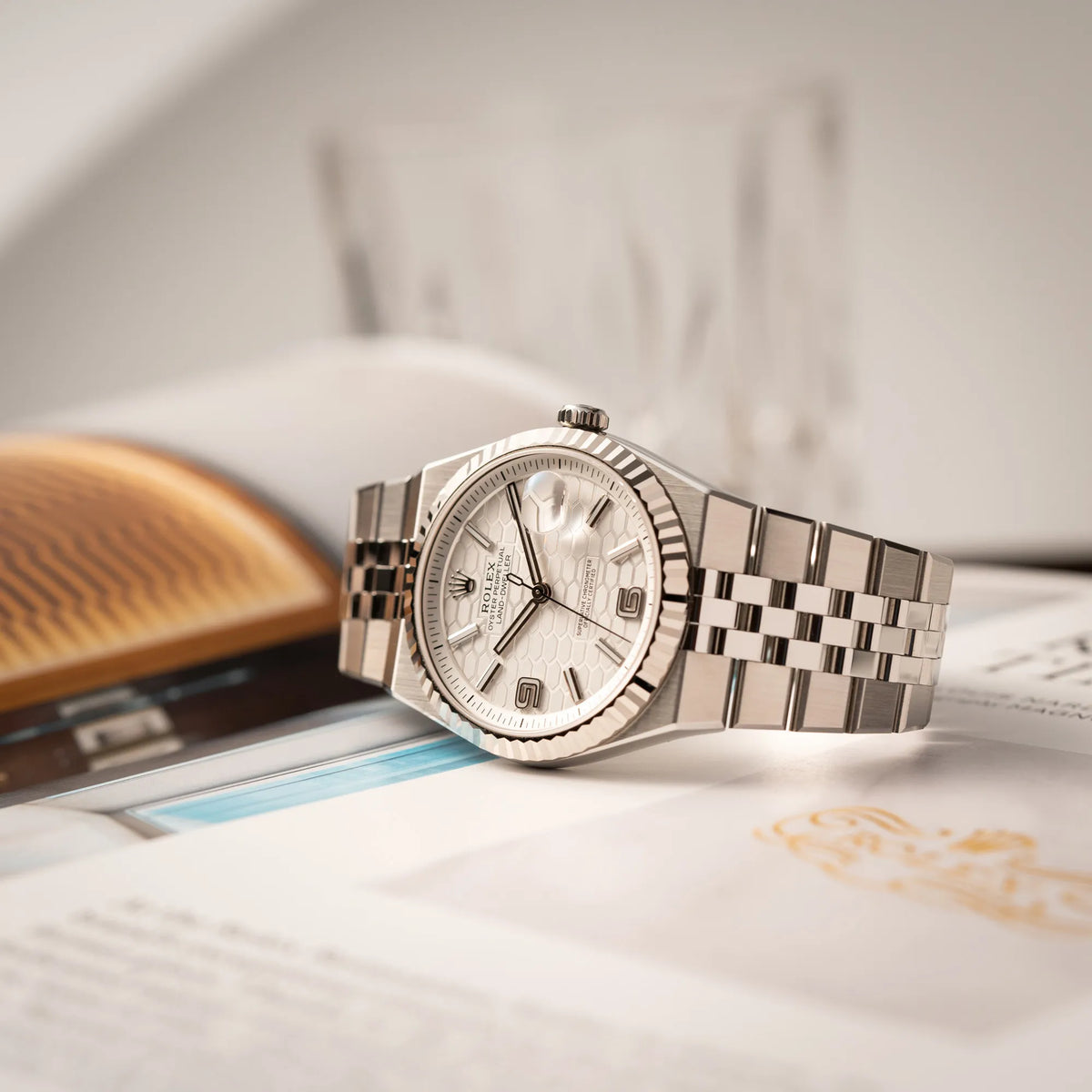 Rolex Land-Dweller 40 der Referenz 127334 im neuwertigen Zustand mit dem weißen Zifferblatt in Waben-Struktur am neuen Flat-Jubilee-Armband liegt auf einem Uhrenmagazin