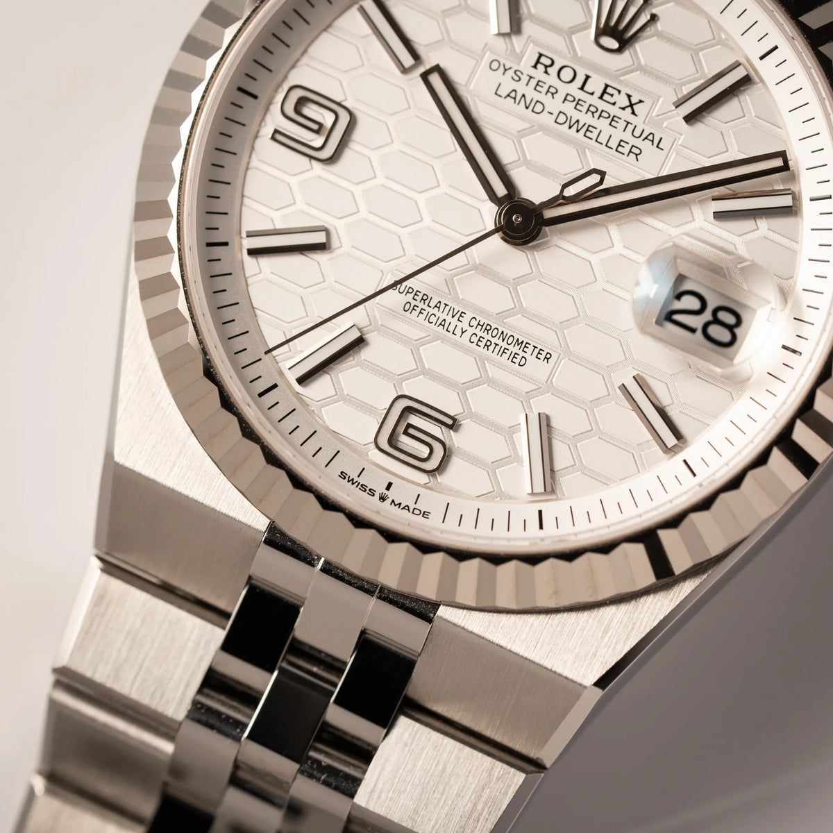 Detailaufnahme der Rolex Land-Dweller 40 der Referenz 127334 im neuwertigen Zustand mit dem weißen Zifferblatt in Waben-Struktur am neuen Flat-Jubilee-Armband bei 6 Uhr