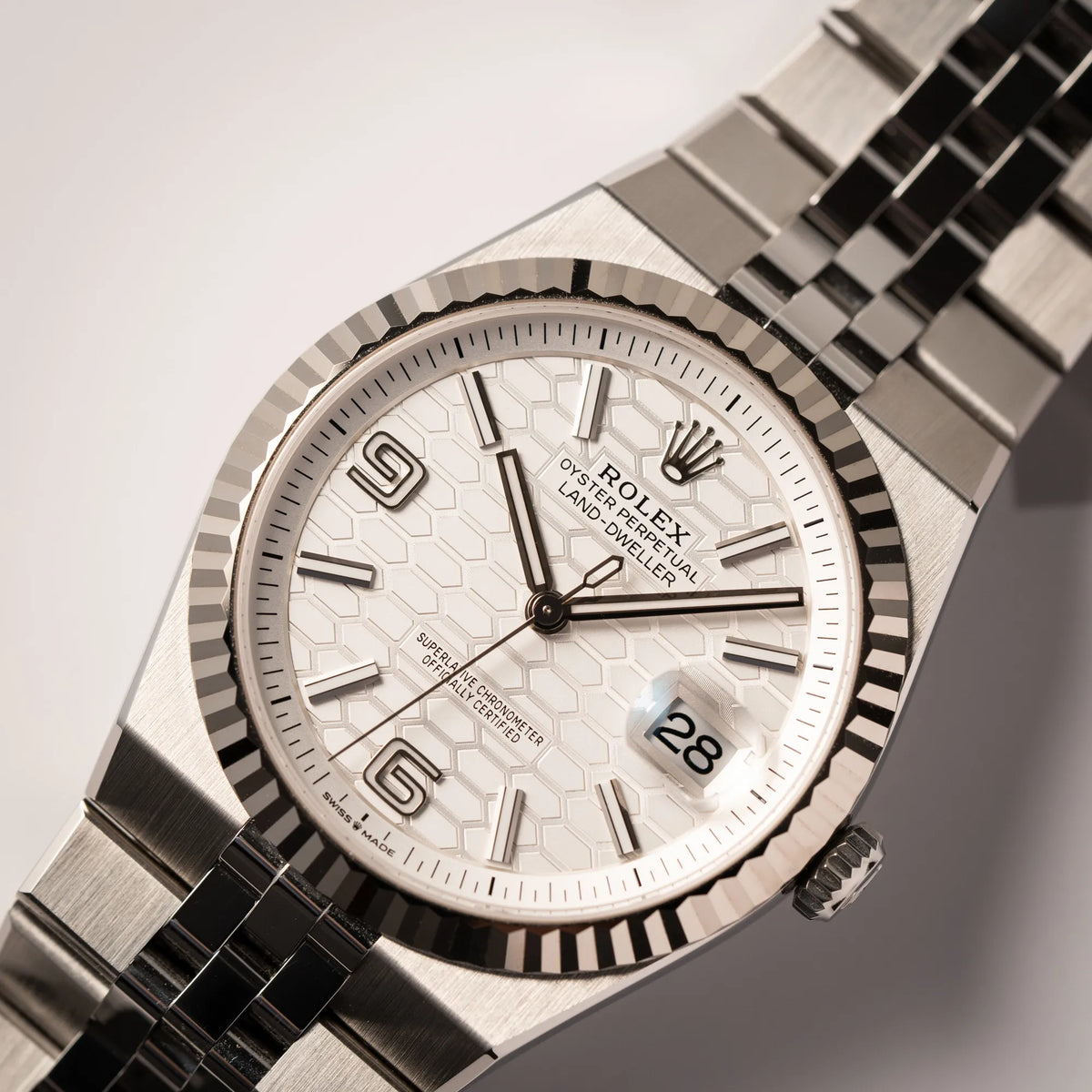 Nahaufnahme der Rolex Land-Dweller 40 der Referenz 127334 im neuwertigen Zustand mit dem weißen Zifferblatt in Waben-Struktur am neuen Flat-Jubilee-Armband