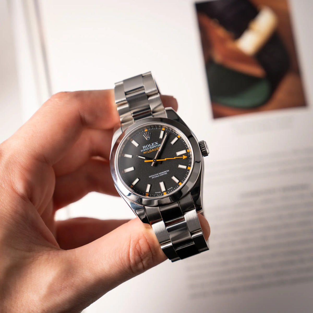 Mann präsentiert die Rolex Milgauss der Referenz 116400 mit schwarzem Zifferblatt und orangen Akzenten in seiner Kamera