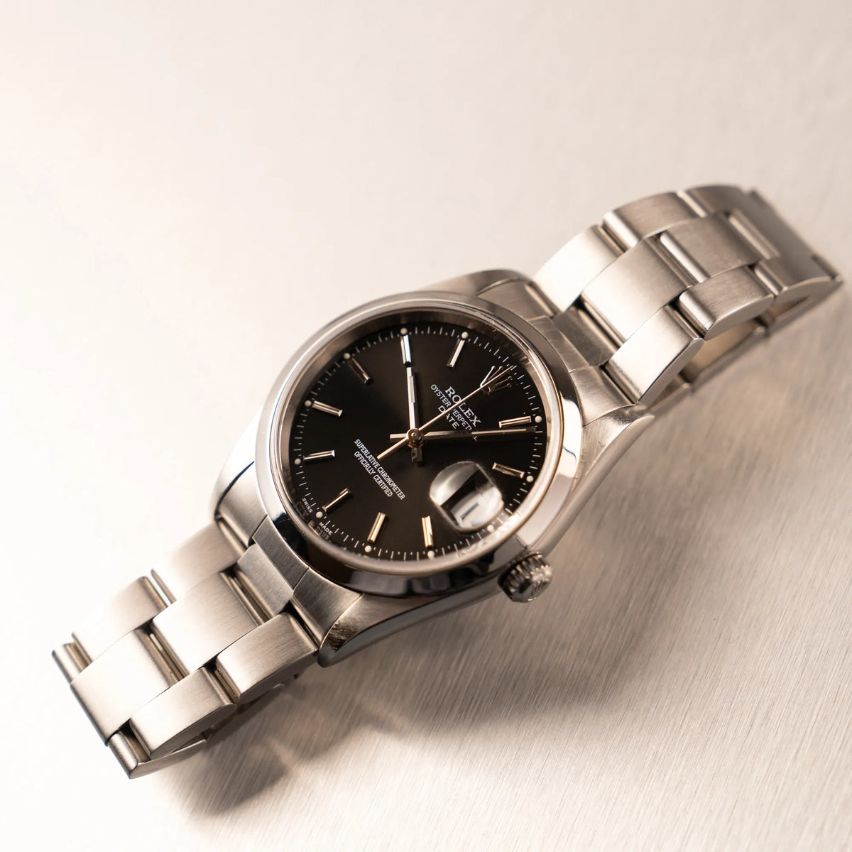 Produktfotografie der auf dem Band liegenden Rolex Oyster Perpetual 34 mit schwarzem Zifferblatt der Referenz 15200 mit glatter Lünette und 34mm Gehäusedurchmesser