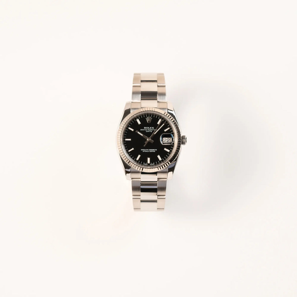 Frontale Ansicht der Rolex Oyster Perpetual Date 34 der Referenz 115234 mit schwarzem Zifferblatt und der geriffelten Weißgold-Lünette