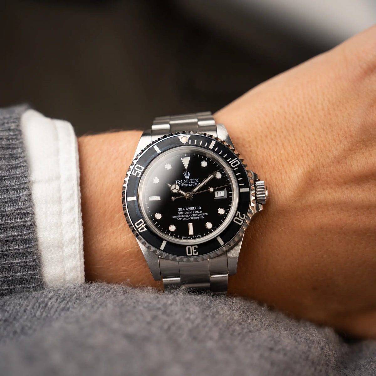 Mann trägt die Rolex Sea-Dweller 4000 der Referenz 16600 mit 40mm-Oyster-Gehäuse und schwarzer Aluminium-Lünetten-Inlay am Handgelenk und blickt auf das Zifferblatt