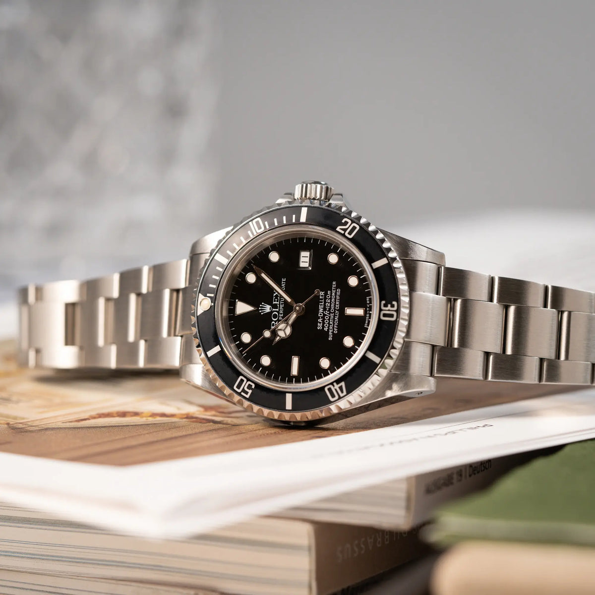 Produktfotografie der seitlich auf dem Gehäuse liegenden Rolex Sea-Dweller 4000 der Referenz 16600 mit 40mm-Oyster-Gehäuse und schwarzer Aluminium-Lünetten-Inlay
