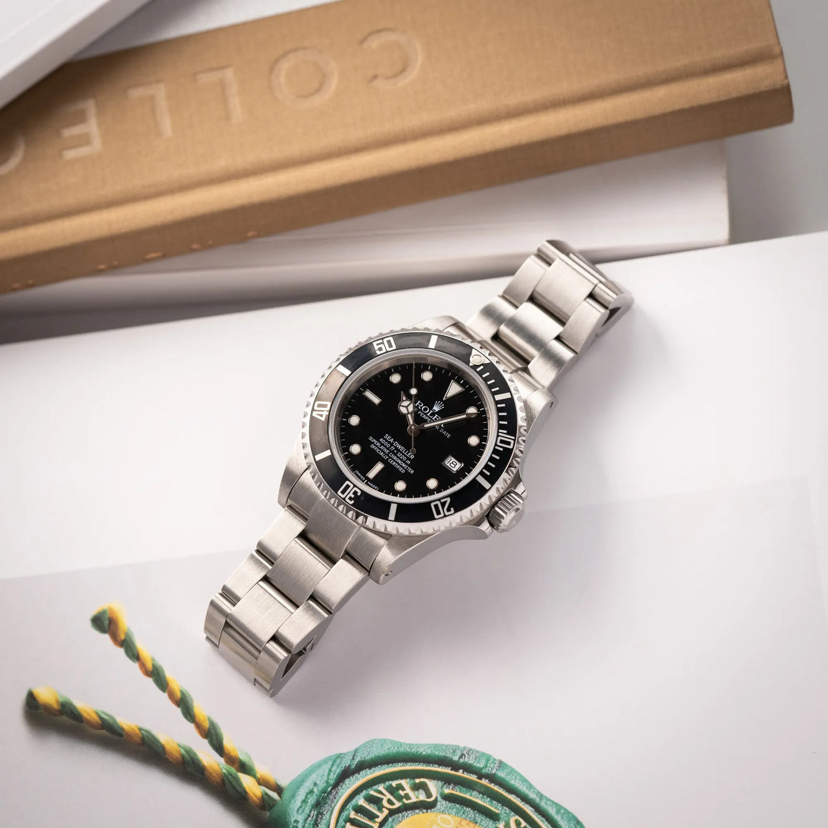 Rolex Sea-Dweller 4000 der Referenz 16600 mit schwarzem Blatt und schwarzer Aluminium-Lünette liegt für eine Produktfotografie flach auf einem Uhrenbuch
