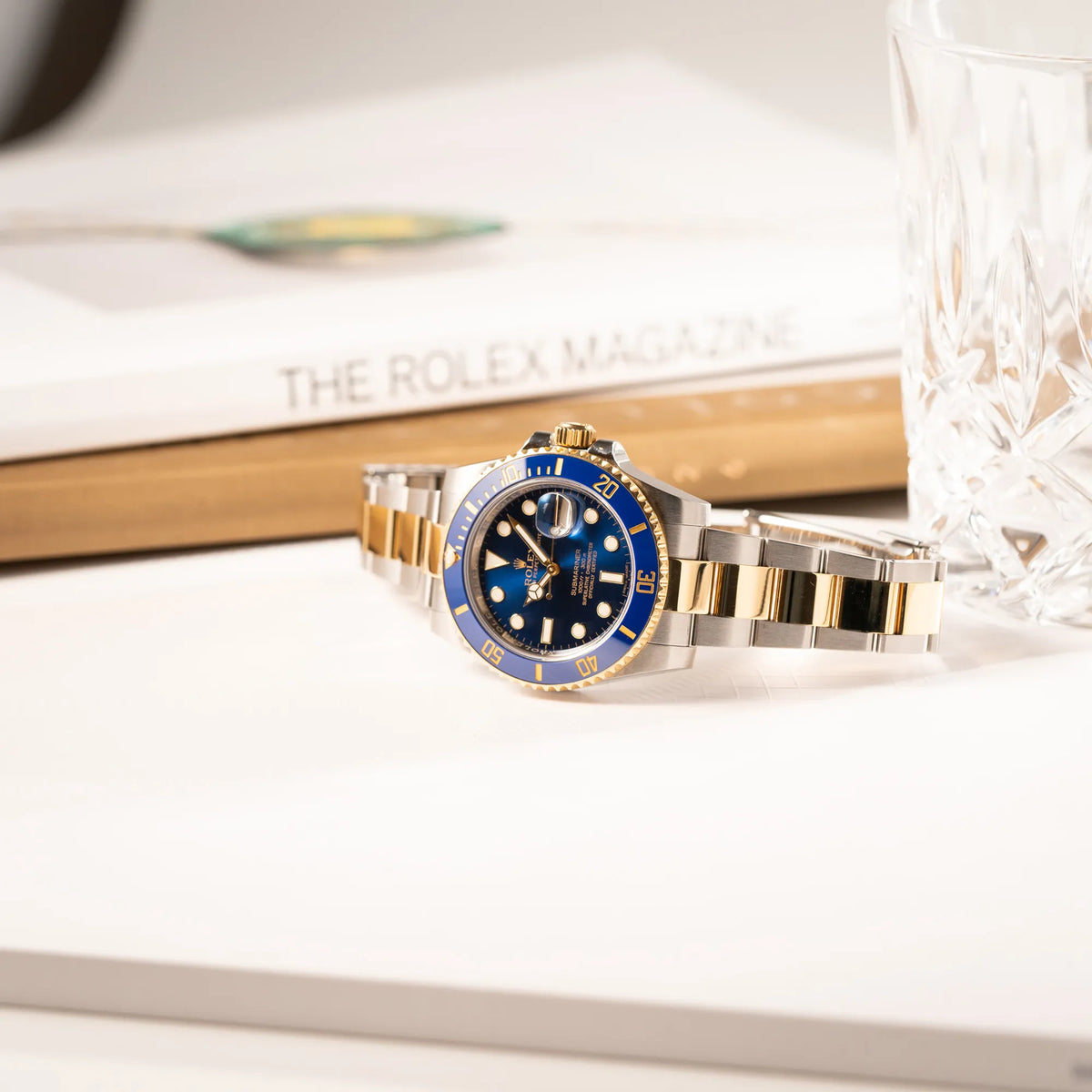 Rolex Submariner Date der Referenz 116613LB in Stahl-Gold mit blauem Zifferblatt - auch mit Nickname Bluesy bennant - am passenden Oytser-Armband in Stahl-Gold liegt seitlich auf dem Uhrengehäuse