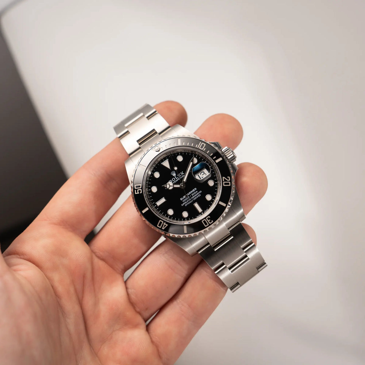 Mann hält die Rolex Submariner Date in schwarz mit Keramik-Lünette am Oyster-Stahlband aus 2023 mit dem 41mm-Oyster-Gehäuse in seiner Hand und präsentiert die Uhr in die Kamera