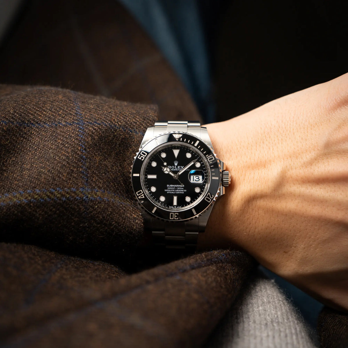 Mann in braunem Sakko trägt die Rolex Submariner Date in schwarz mit Keramik-Lünette am Oyster-Stahlband aus 2023 mit dem 41mm-Oyster-Gehäuse